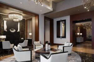 A luxurious living room with four white armchairs around a round coffee table. Dark wood and marble accents, modern lighting.