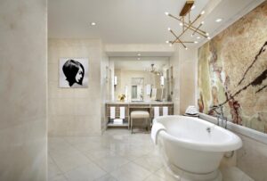 Luxurious bathroom with a freestanding tub, mirrored vanity, and a dramatic amber/red-veined stone accent wall.