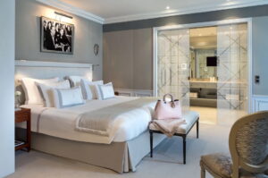 Bedroom with a large bed, white bedding, black and white artwork, dark wood nightstand, and sliding glass doors.