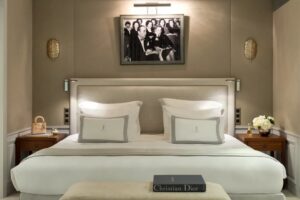 A luxurious bedroom features a large bed with white bedding, wooden nightstands, and a vintage black and white photograph.
